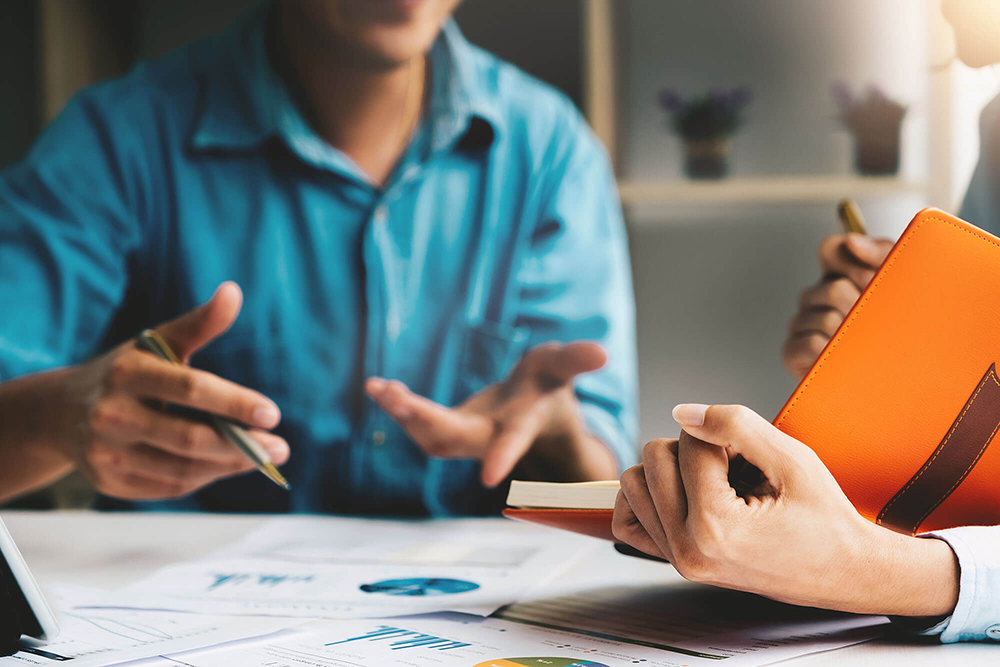 professionals_working_desk_documents_holding_orange_folder